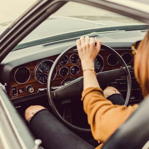 A woman is driving a luxury car on the road.